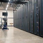 Armários metálicos com servidores, dispositivos de rede e cabos em um data center moderno.