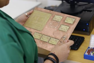 Técnico examina uma placa de circuito impresso em um laboratório de eletrônica.