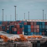 Contêineres coloridos empilhados em uma área portuária industrial.