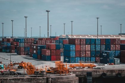 Contêineres coloridos empilhados em uma área portuária industrial.