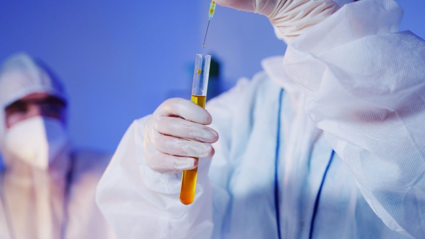 Cientista usando equipamento de proteção manipula um tubo de ensaio em um laboratório.